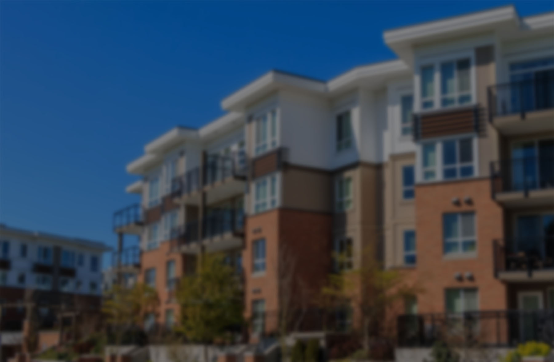 A multistory apartment community under a blue sky.