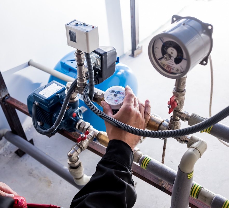 A water meter installed on supply piping next to valves and pressure gauges.